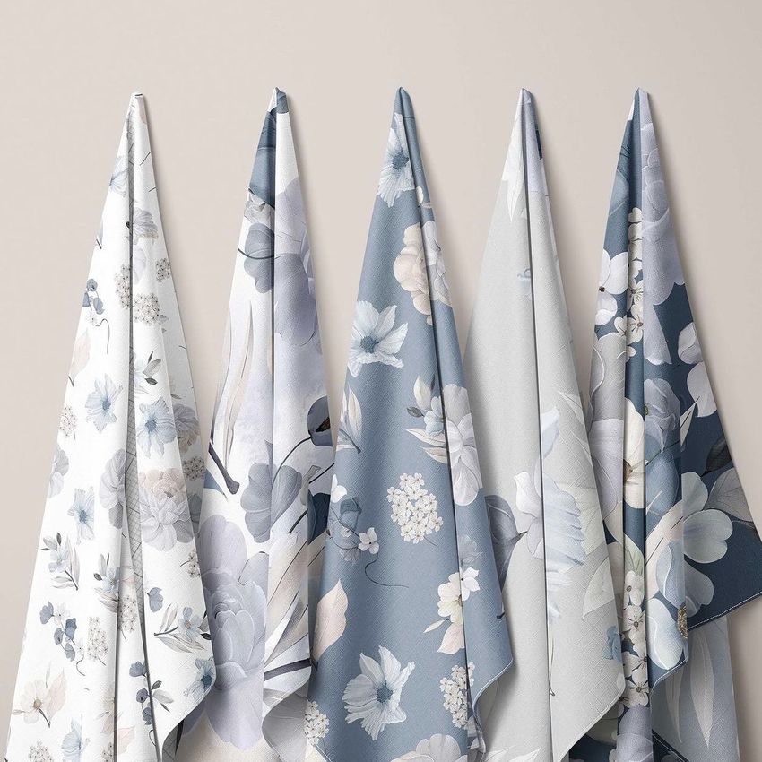 Hanging fabrics mockup featuring four cloth panels with dusty blue and white floral patterns against a neutral wall background.