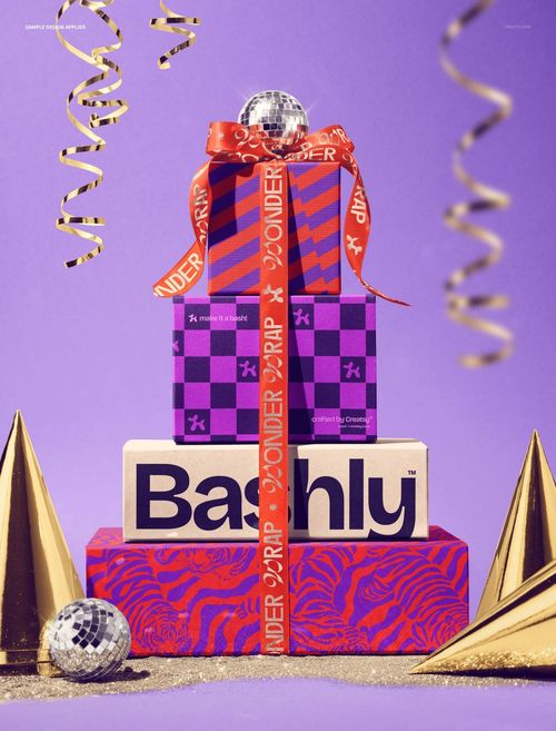 Front view of a mockup featuring three stacked gift boxes with vibrant patterns, satin ribbon, and festive props.