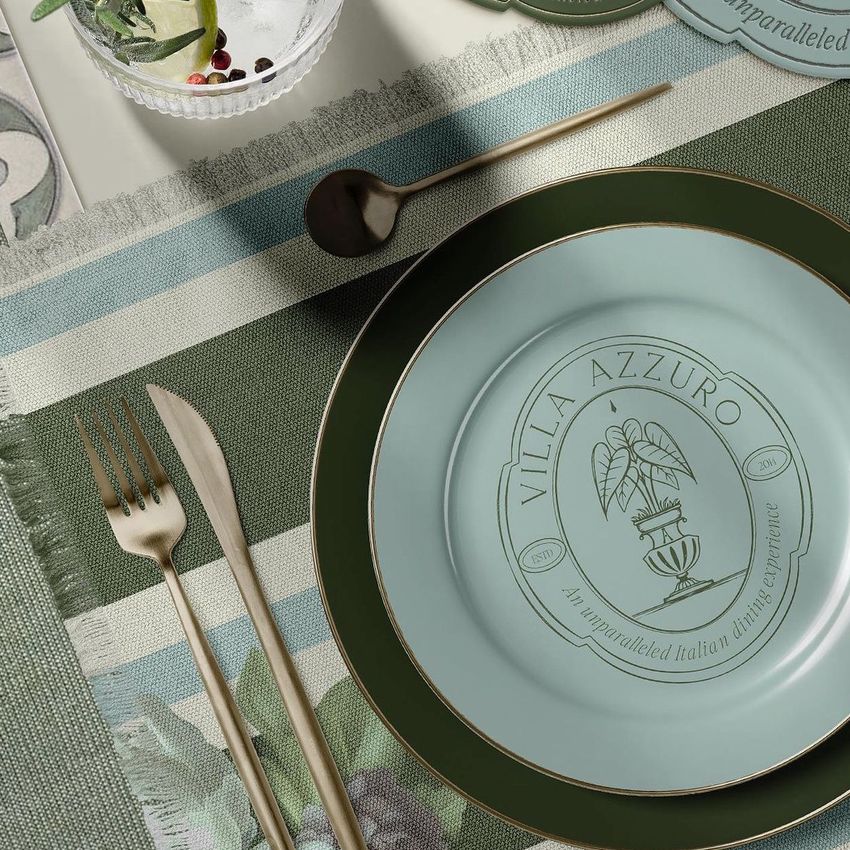 Fringed placemat and plates mockup showing a green and blue striped placemat with gold cutlery and decorative plates.