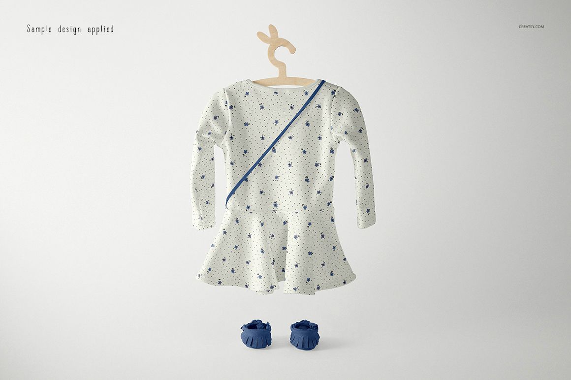 Long-sleeve baby dress mockup with a blue floral pattern, displayed on a bunny-shaped hanger with matching shoes.