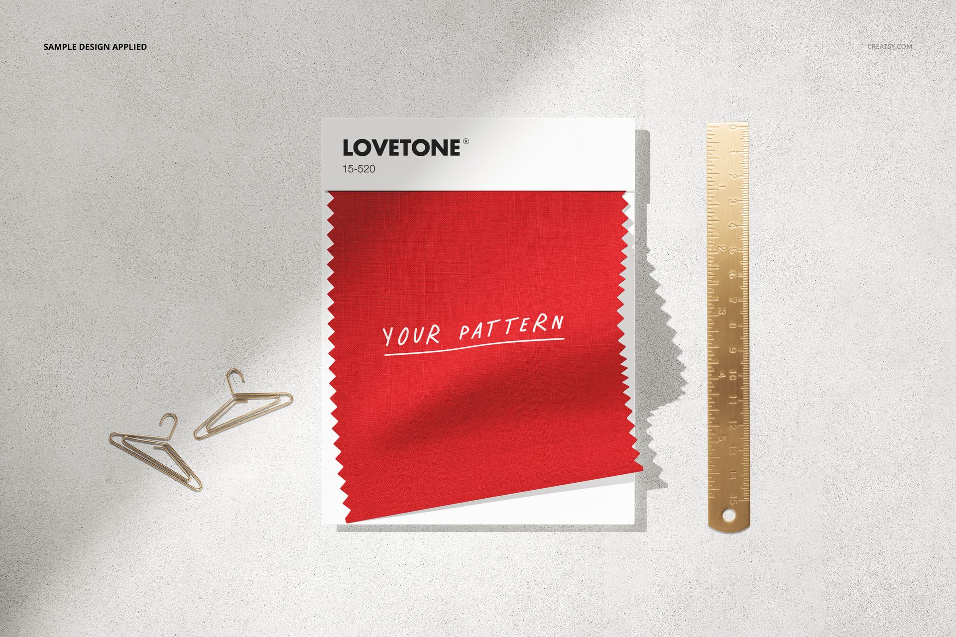 Stationery mockup featuring a square card with red fabric swatch, gold ruler, and two mini hangers on a light surface.