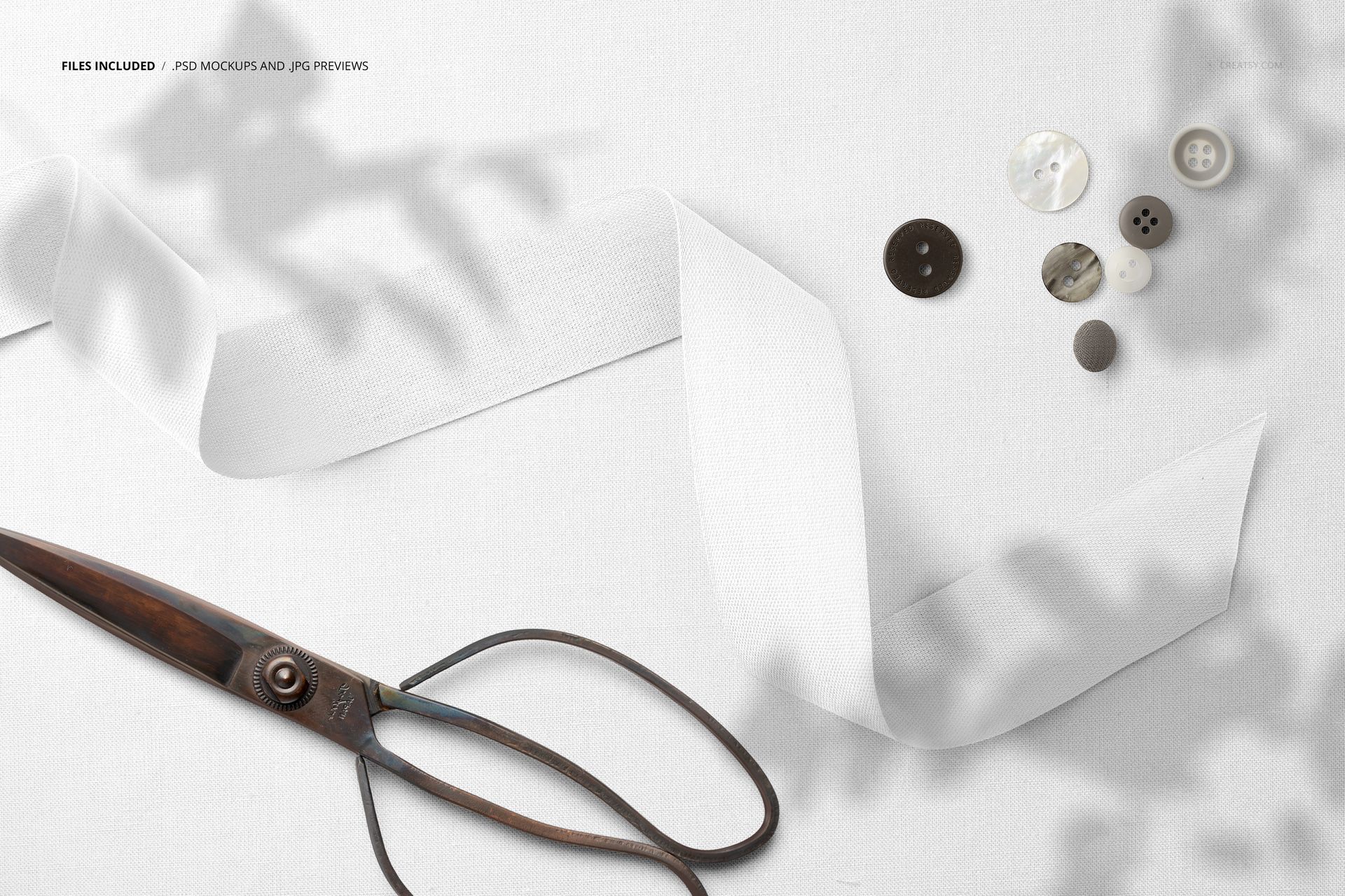 Mockup scene featuring wide cotton ribbon, metal scissors, and buttons arranged on a plain white textile, top perspective.