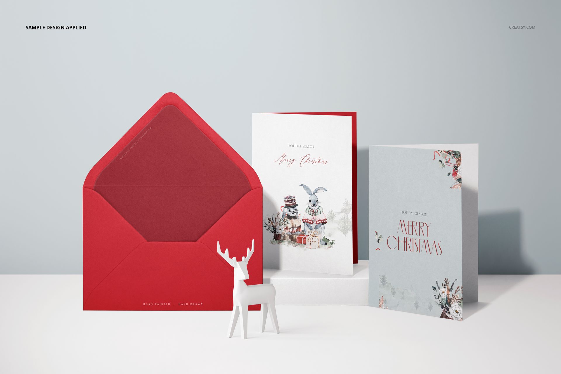PSD mockup featuring three vertical greeting cards with seasonal patterns, a red envelope, and a decorative white deer.
