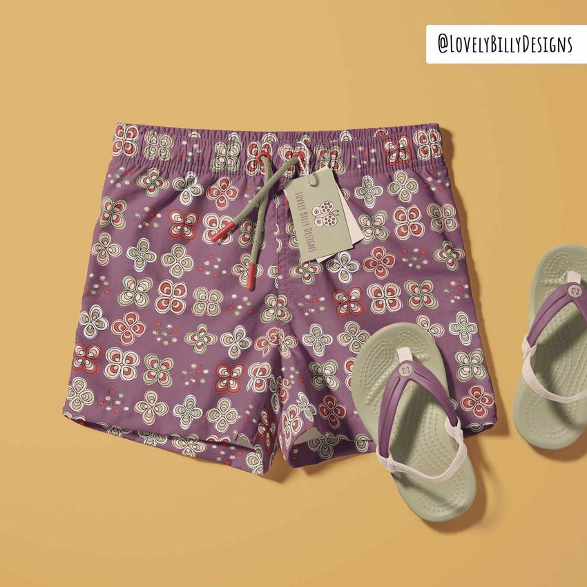 Kids swim shorts mockup featuring purple shorts with a colorful butterfly pattern, displayed on a solid tan background with sandals and a tag.