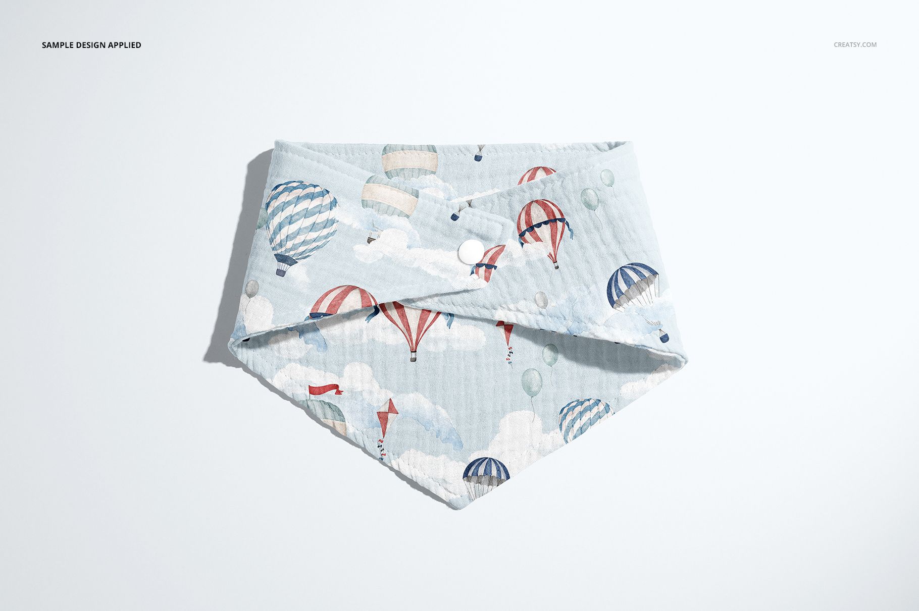 PSD mockup of a baby muslin bandana displayed flat, decorated with colorful hot air balloons and cloud motifs.