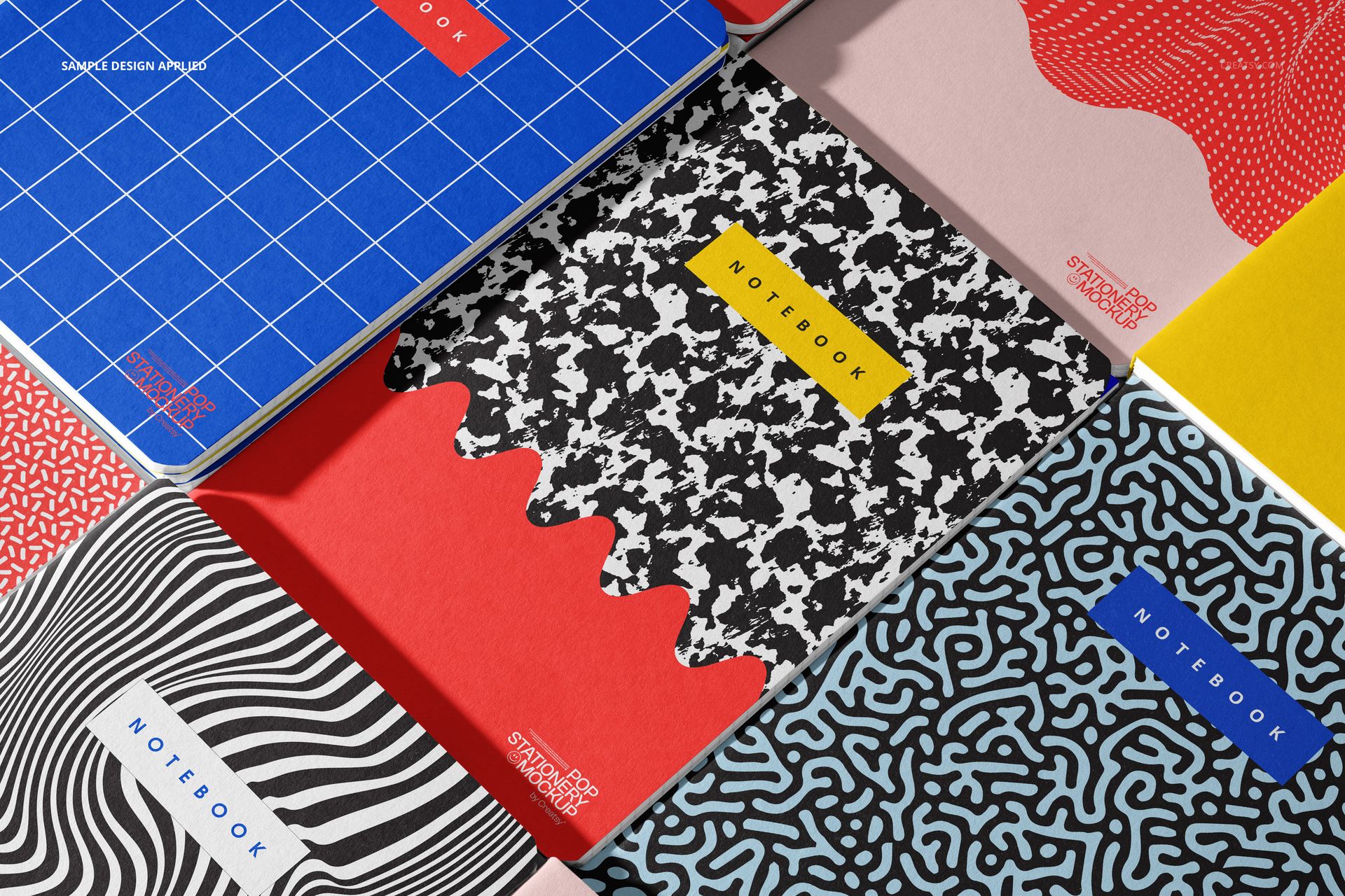 PSD mockup showing several stationery notebooks with geometric and wavy patterns in blue, red, black, and white.