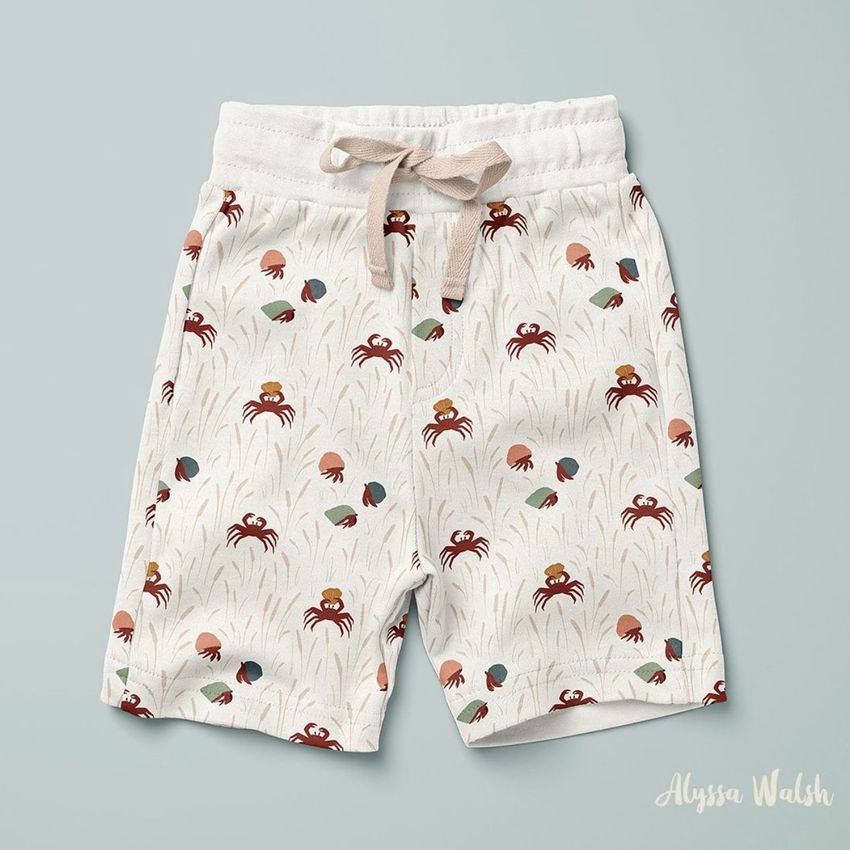 Kids cotton shorts mockup featuring a playful crab and seashell pattern on a light background, shown from above on a pale surface.