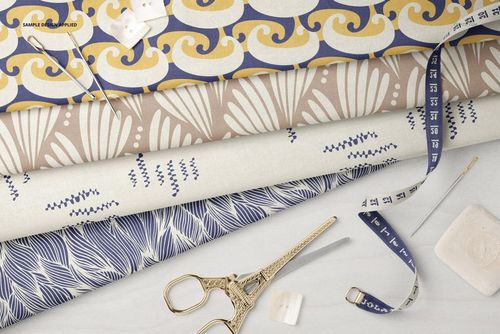 Four folded cotton fabrics with different designs, displayed with tailor tools on a light surface in a PSD mockup.