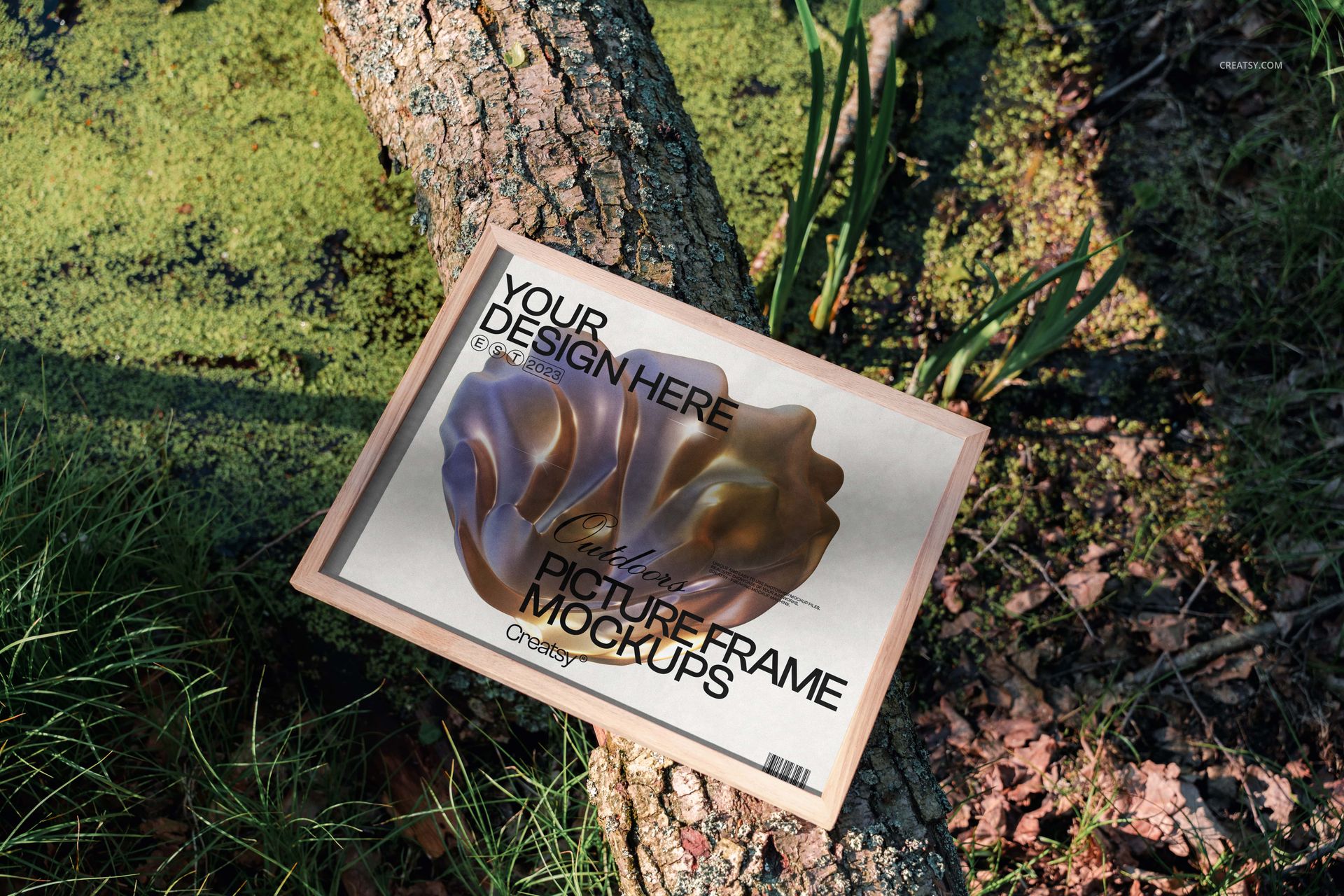 Wooden picture frame mockup resting on a mossy tree trunk outdoors, surrounded by green grass and plants.