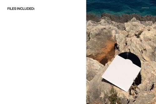 Top view of a 7 inch black vinyl record mockup in a white cover placed on rugged rocks near the ocean.