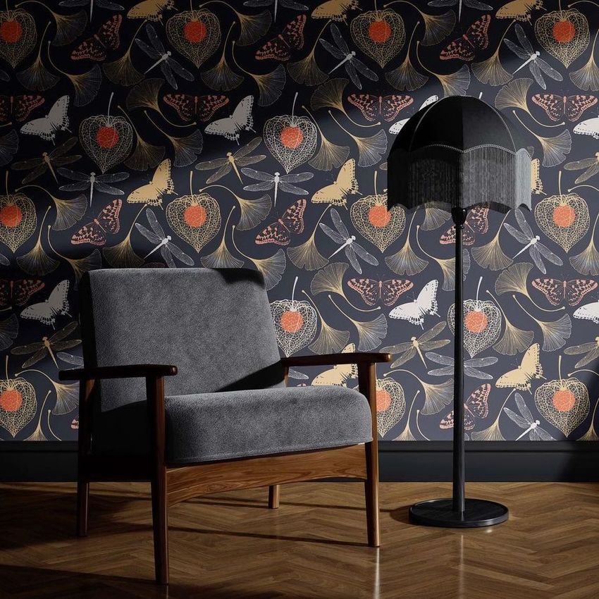 Interior mockup featuring a gray upholstered armchair and a black floor lamp with fringe, set against a dark floral wallpaper.