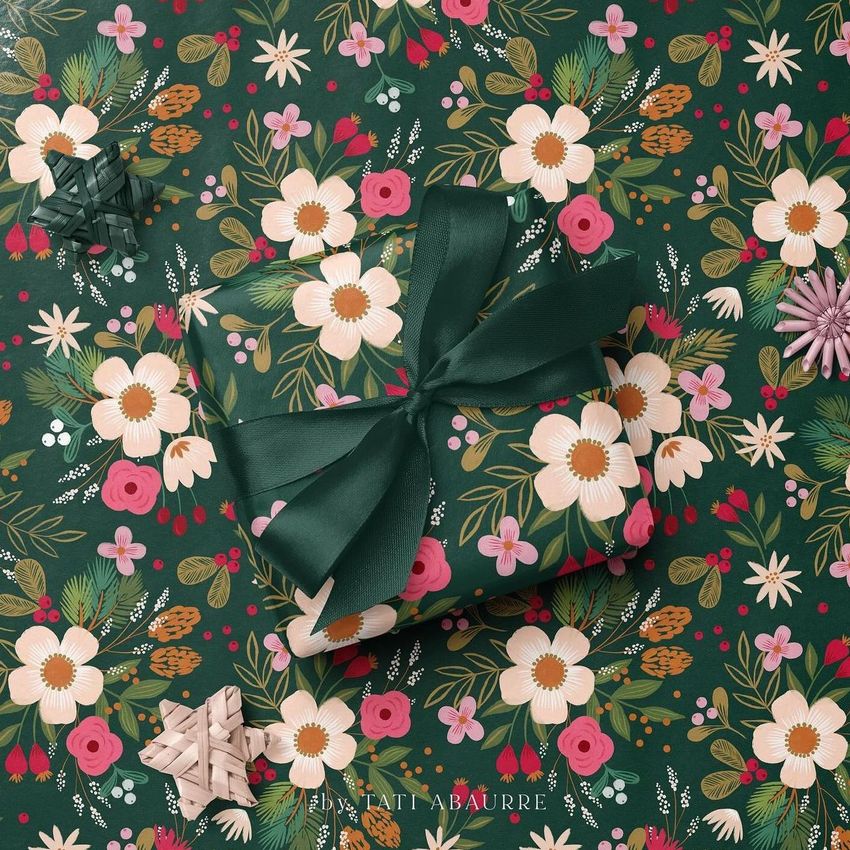 Square gift box mockup wrapped in green floral paper with a dark green ribbon, set on matching patterned wrapping paper.