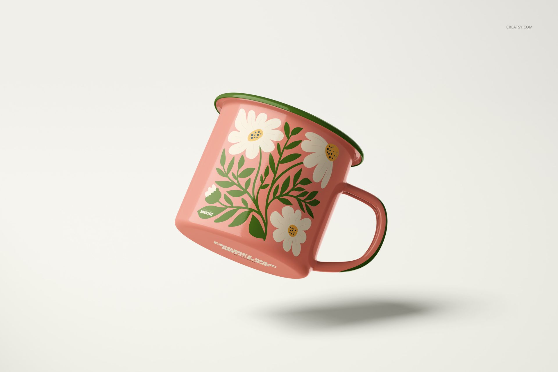 Enamel mug mockup featuring a pink surface, green edge, and white flowers, displayed at an angled side view.