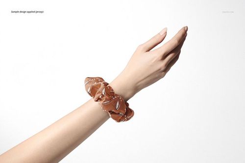 Brown patterned hair scrunchie mockup displayed on a raised hand against a plain white background, side view.