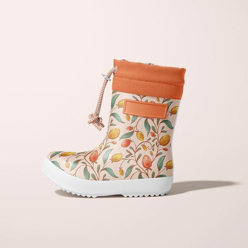 Rain boots mockup featuring a side view of a single boot with a colorful botanical pattern and an orange cuff on a light background.