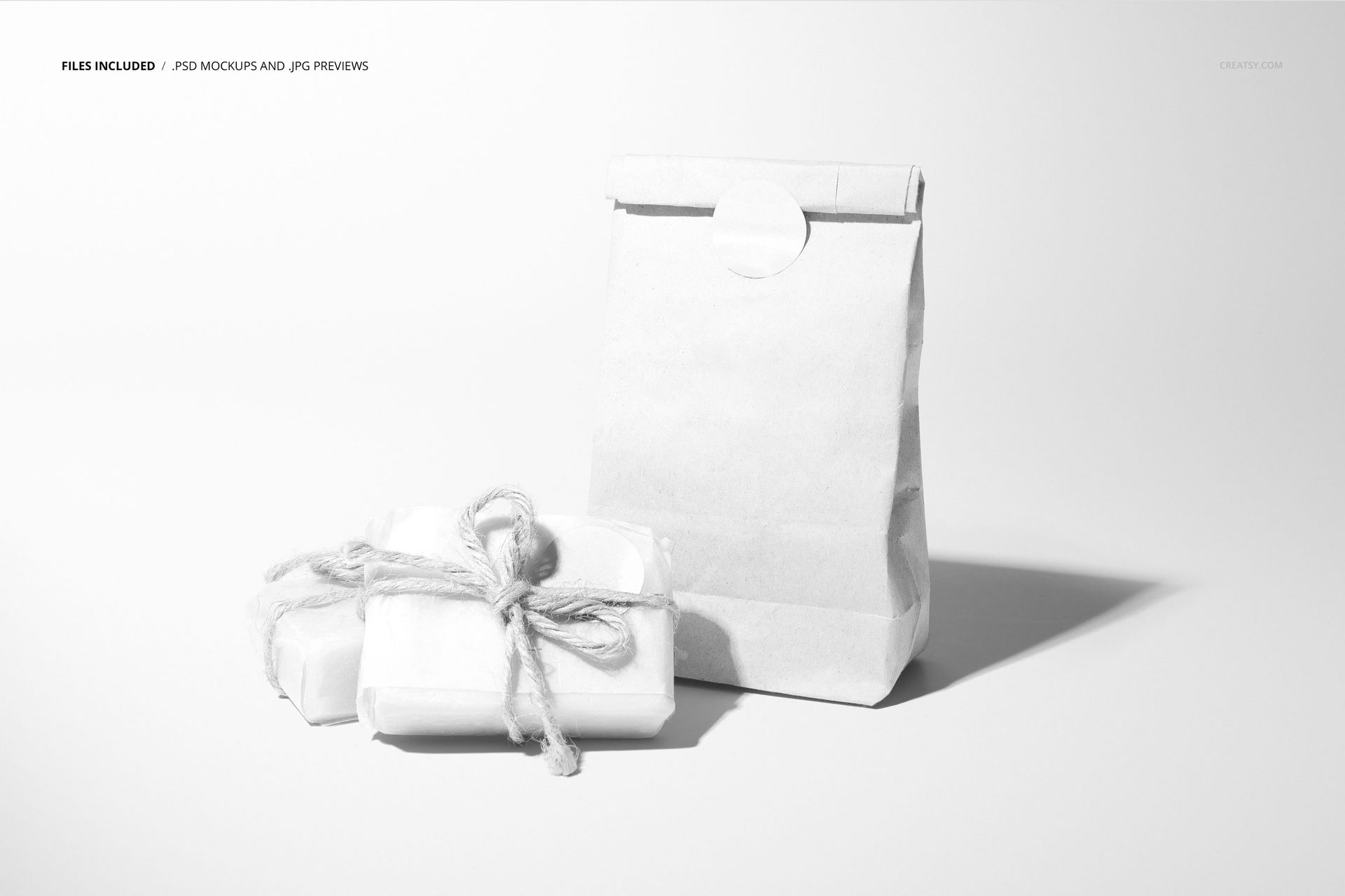 Front view of handmade soap packaging mockup featuring a paper bag and two wrapped soap bars tied with string on a white surface.