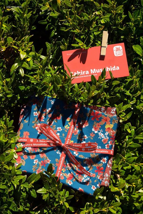 PSD mockup showing colorful floral fabric swatches and a red card clipped to a shrub, viewed from above.