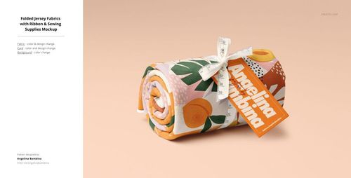 Folded jersey fabric mockup featuring orange and green fruit print, ribbon, and label, on a soft peach surface.