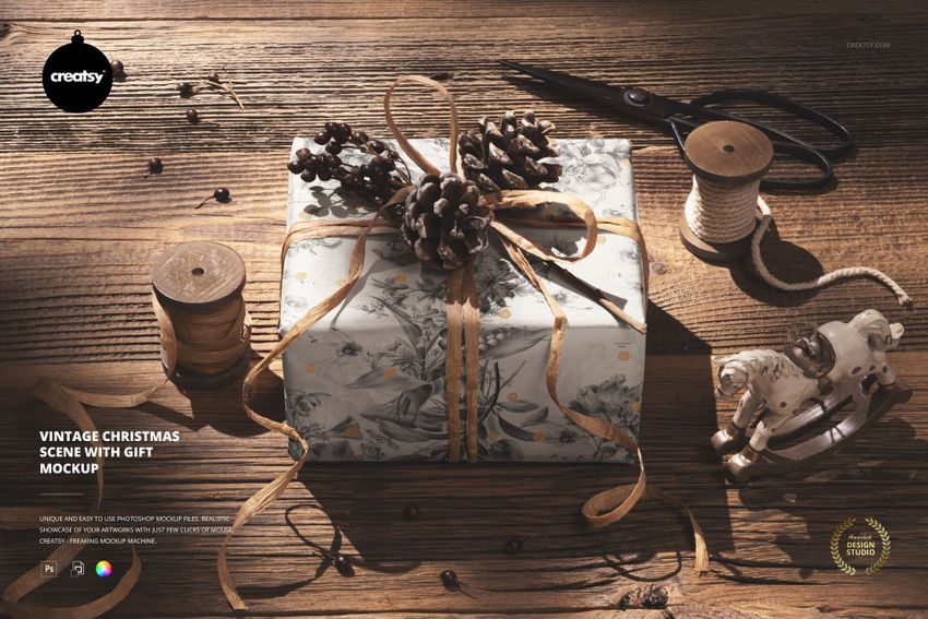 PSD mockup of a holiday present with botanical wrapping paper, pinecone accents, and crafting tools in a festive setting.