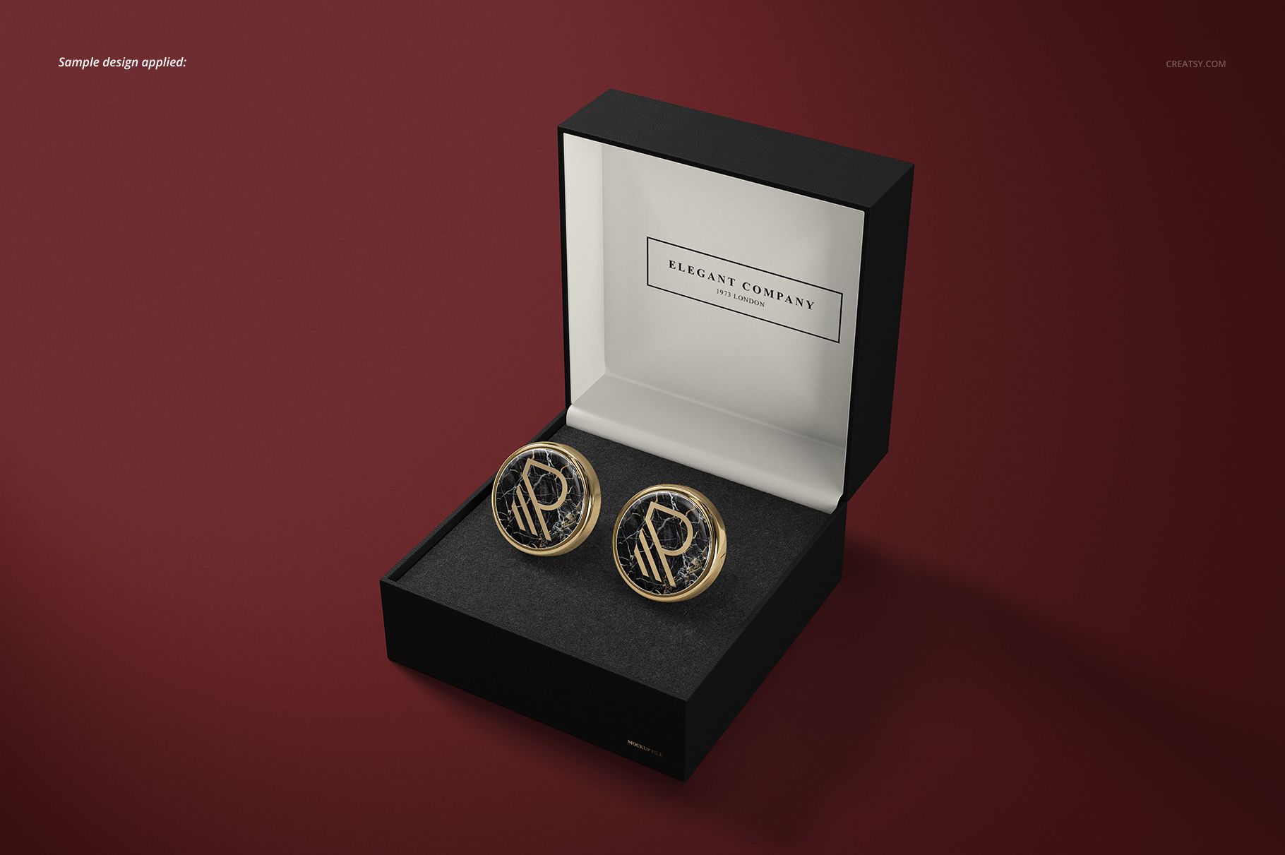 Cufflinks mockup featuring two circular accessories with gold trim and black detail, presented in an open box against a dark red backdrop.