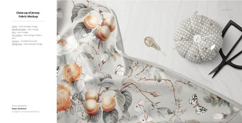 Close-up of a fabric mockup featuring a floral and fruit pattern, displayed on a flat surface with sewing tools nearby.