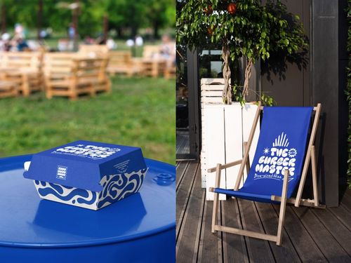 Blue and white burger box mockup with abstract patterns placed on a round table in a park setting.