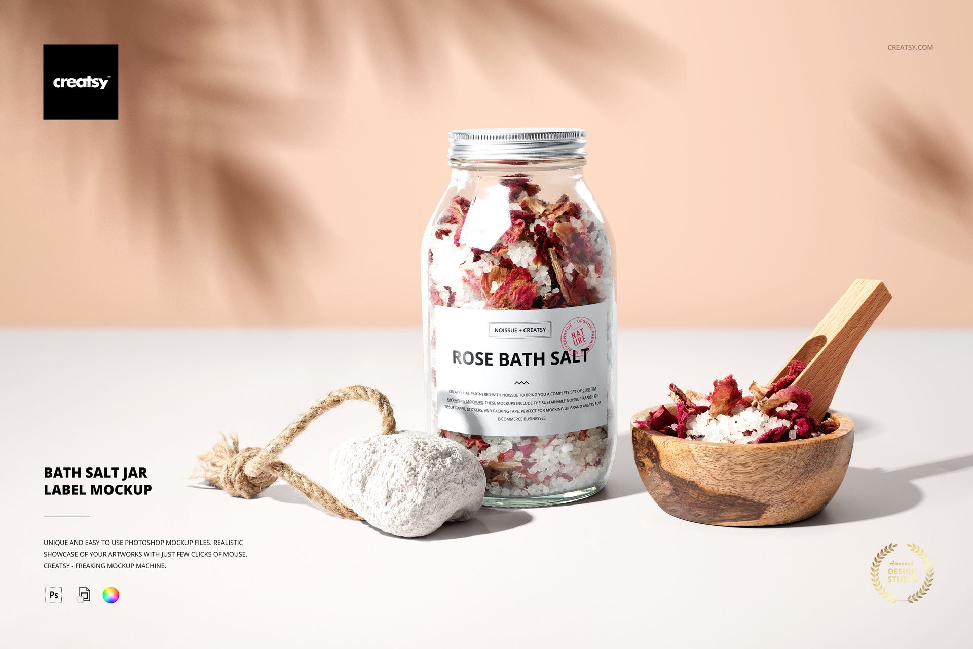 Front view of a bath salts jar mockup with a white label, next to a wooden bowl and a pumice stone on a beige surface.