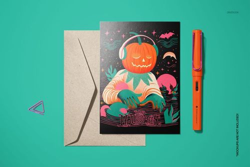 Halloween card mockup with vibrant pumpkin DJ artwork, shown beside a brown envelope and orange pen on a turquoise surface.