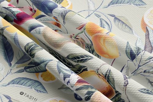 Close-up view of bullet fabric mockup featuring a folded textile with a botanical and fruit pattern in soft colors.