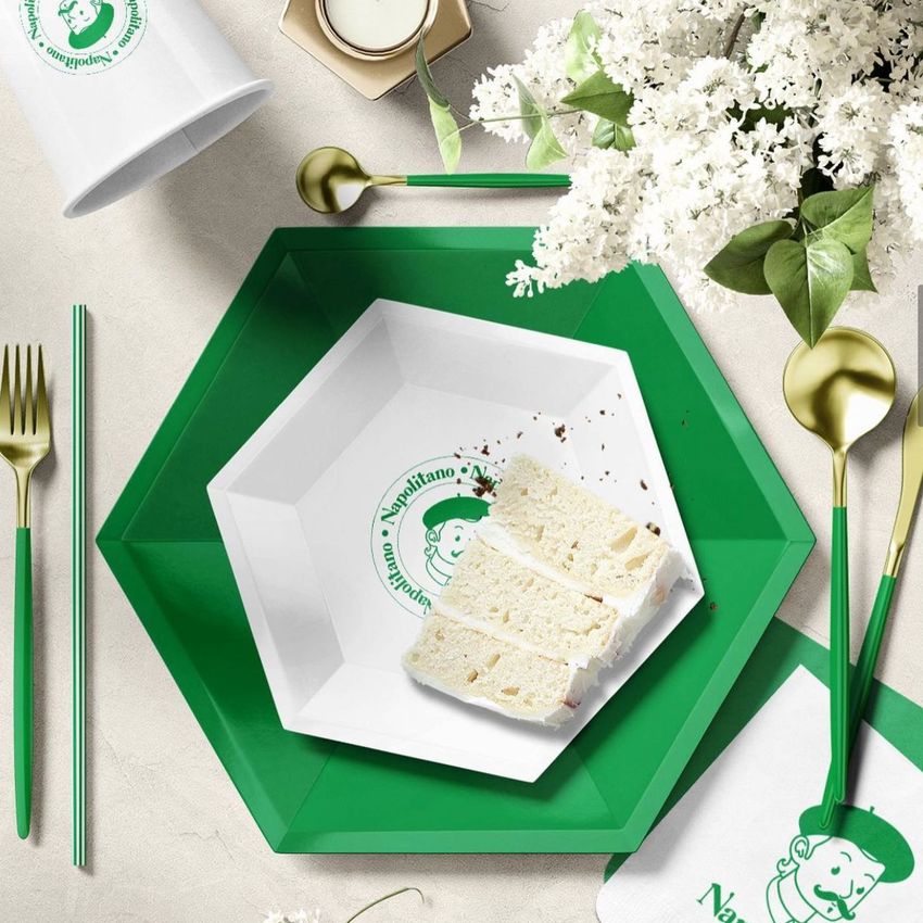 Party supplies mockup featuring a green and white hexagonal plate with cake slices, gold cutlery, and floral decor on a light surface.