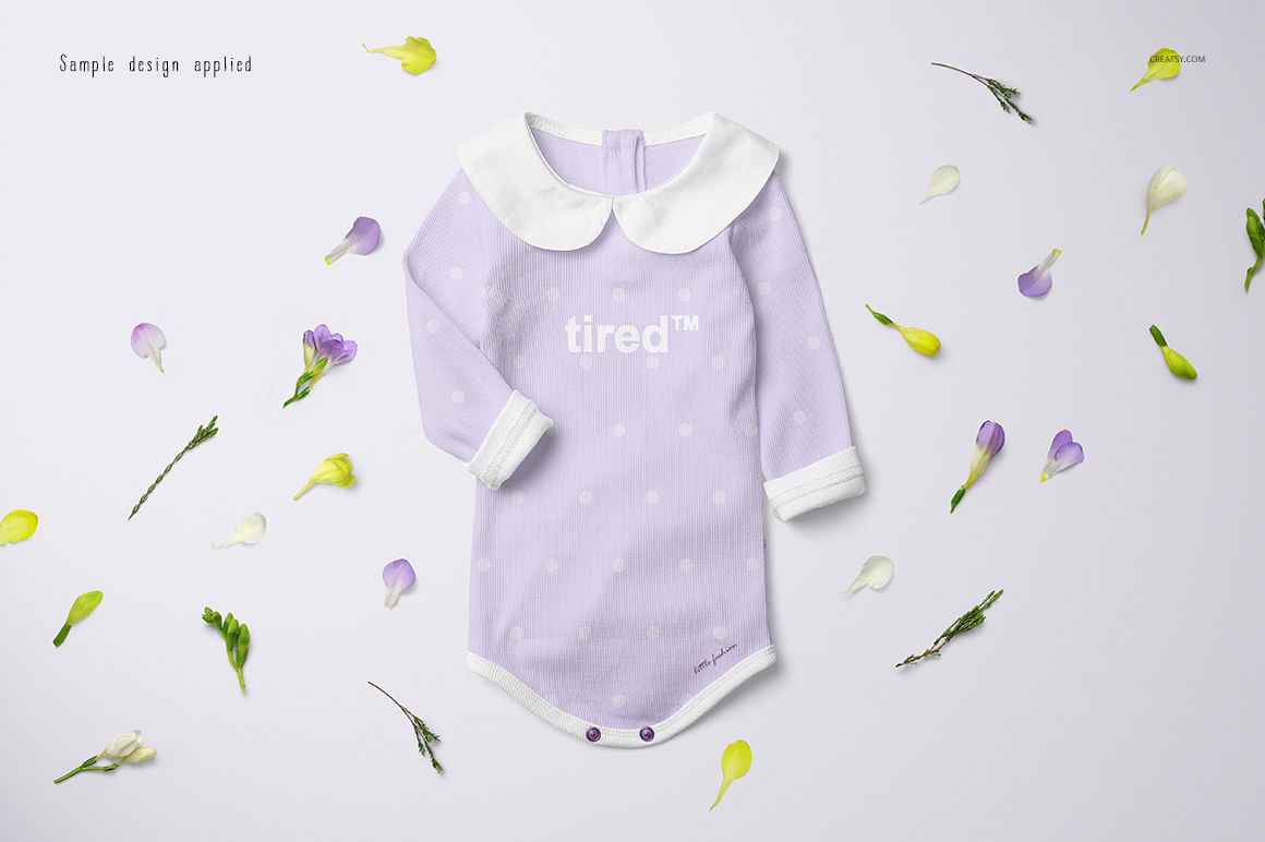Long-sleeve baby romper mockup in light purple with white polka dots, front view, surrounded by flower petals.