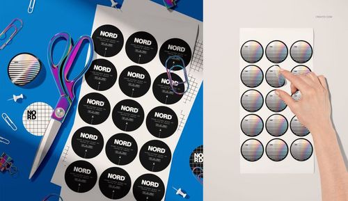 PSD mockup displaying round stickers with modern black and white designs on a sheet, scissors and paperclips nearby.