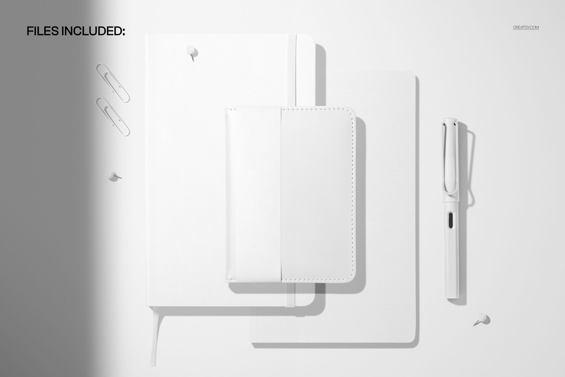 Top view of leather calendars and notebook mockup in white, with pen, paper clips, and push pins on a light background.
