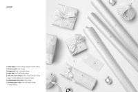 Top view of Christmas wrapping paper mockup with three rolls, four wrapped gifts, ribbons, and paper ornaments on a light background.