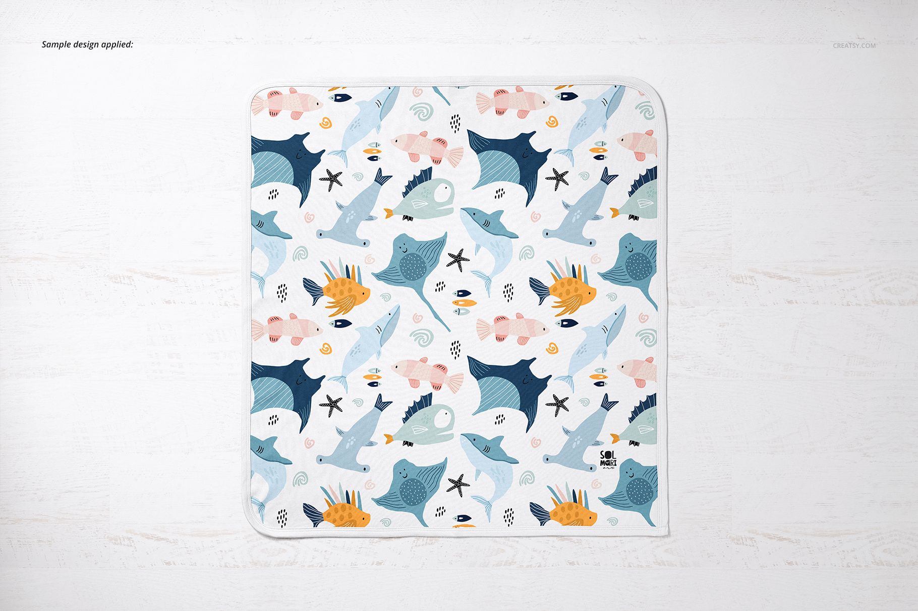 Square cotton baby blanket mockup featuring colorful marine life illustrations, shown from above on a light background.