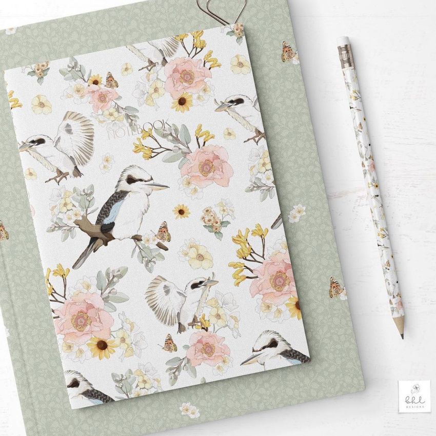 Stationery mockup featuring a floral and bird patterned notebook on a green folder with a matching pencil on a white surface.