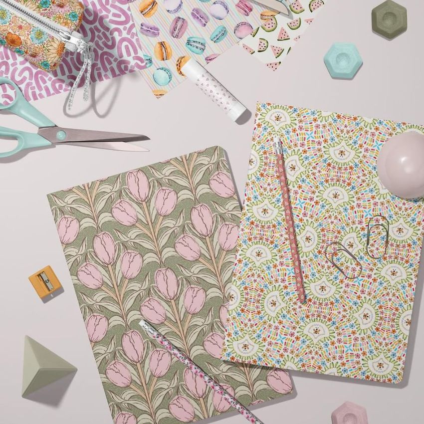 Stationery mockup featuring two A4 notebooks with floral and geometric covers, surrounded by scissors, pencils, and patterned paper.