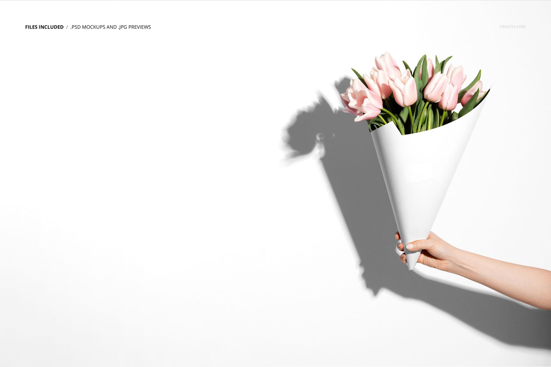 PSD mockup showing a floral bouquet in a minimalist white cone packaging, held by a hand with shadow on the wall.