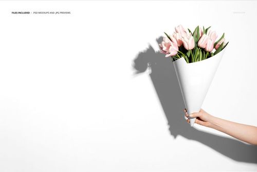 PSD mockup showing a floral bouquet in a minimalist white cone packaging, held by a hand with shadow on the wall.