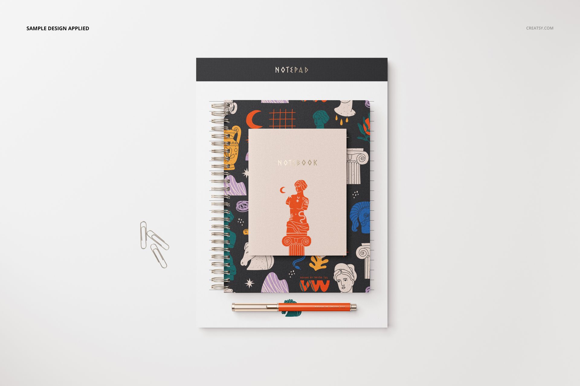 Stationery set mockup featuring a spiral notebook, notepad, and pen arranged on a white surface in top view.