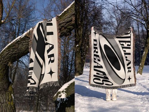 PSD mockup of a rectangular jacquard blanket with geometric and typographic pattern, photographed in a snowy park setting.