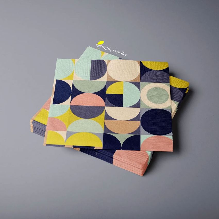 Paper napkins mockup featuring a geometric pattern in pastel colors, stacked on a smooth gray surface, viewed from above.