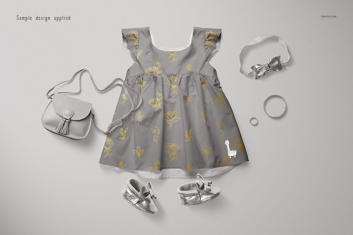 PSD mockup of a baby dress in gray with yellow botanical prints, shown with matching silver accessories on a light background.