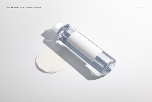 PSD mockup of a clear cosmetic bottle with an empty white label and a cotton pad, displayed from a front angle.