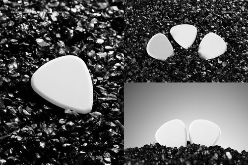 White guitar picks displayed on jagged black gravel, shown in single, double, and trio arrangements in a mockup set.