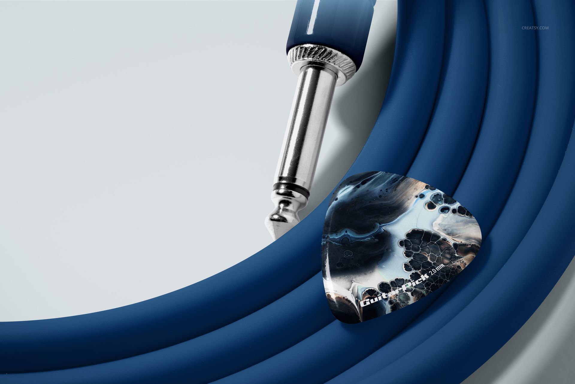 PSD mockup showing a textured guitar pick and a metallic jack connector resting on a blue coiled cable.