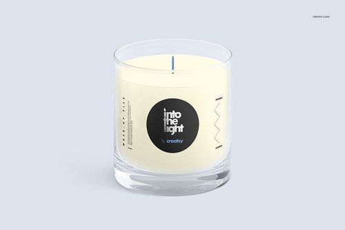 Ultimate Scented Candle mockup with transparent glass holder, white wax, and minimalist label, displayed on a pale surface.