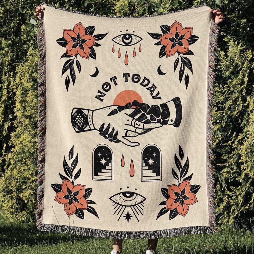 Woven throw blanket mockup held outdoors, featuring bold graphic hands shaking, stylized eyes, flowers, and abstract shapes on a beige background.