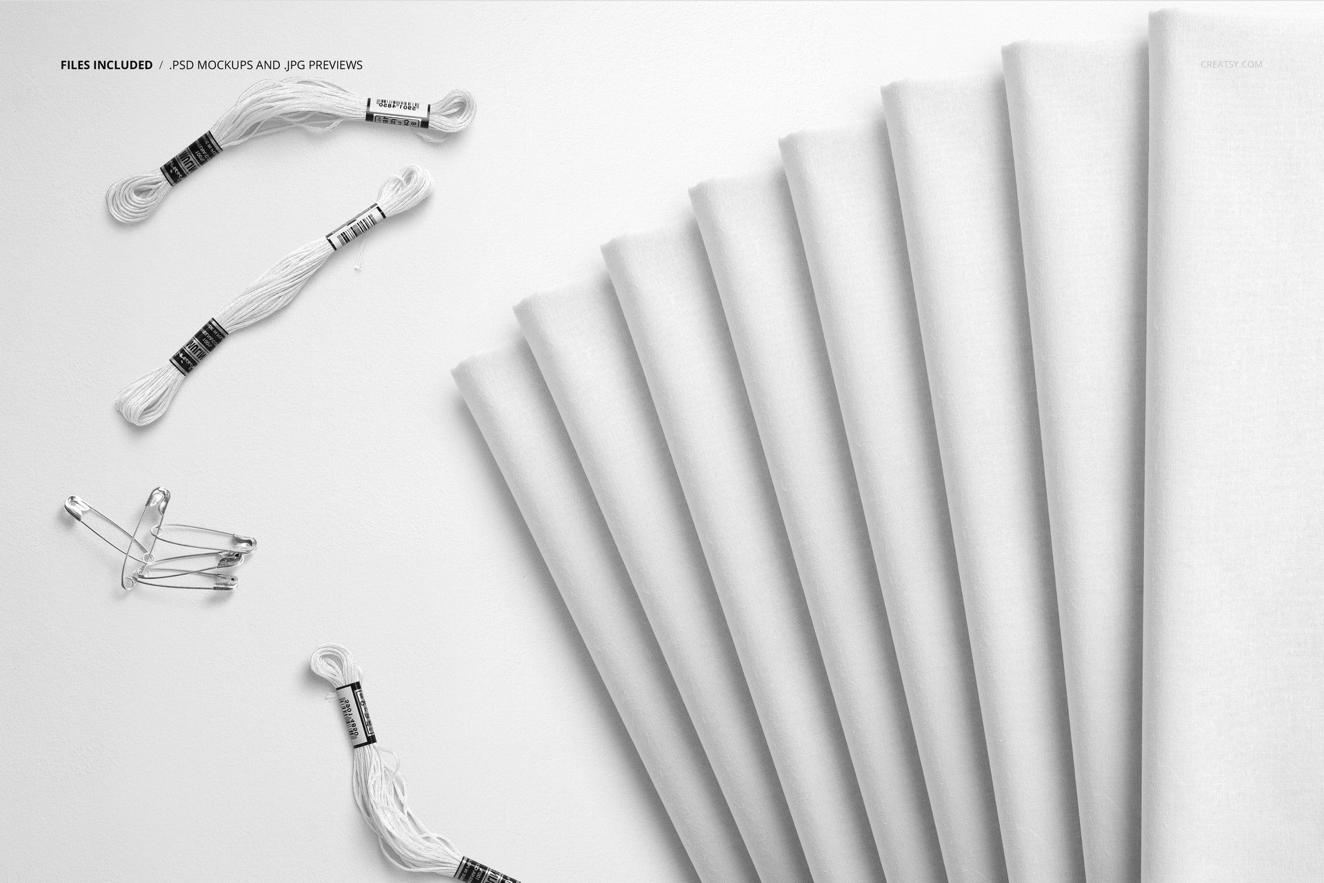 PSD mockup showing neatly folded textiles on a light background, with sewing accessories placed on the left side.