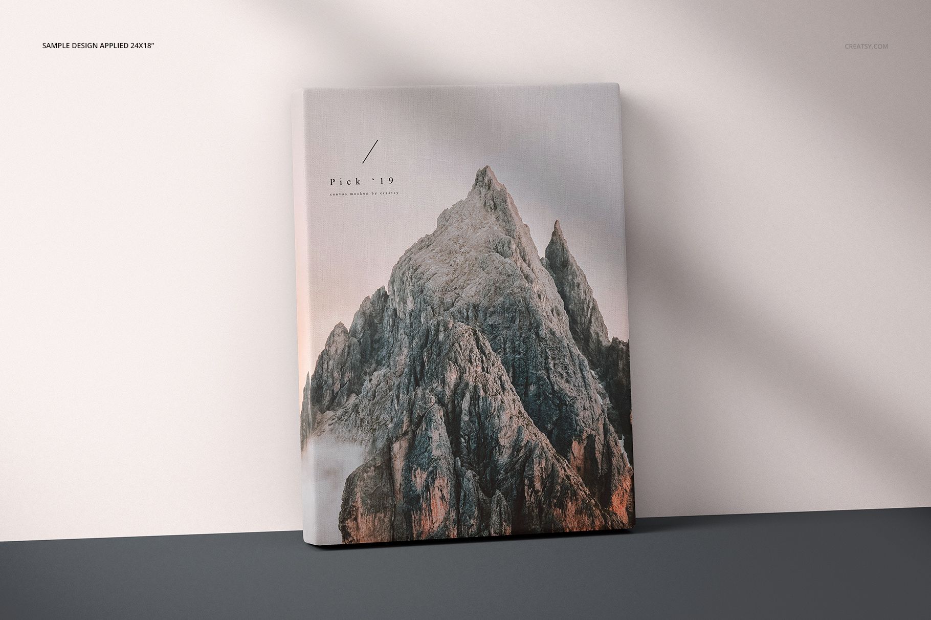 Front view of a thick canvas print mockup with a mountain artwork, standing against a light wall with soft shadows.